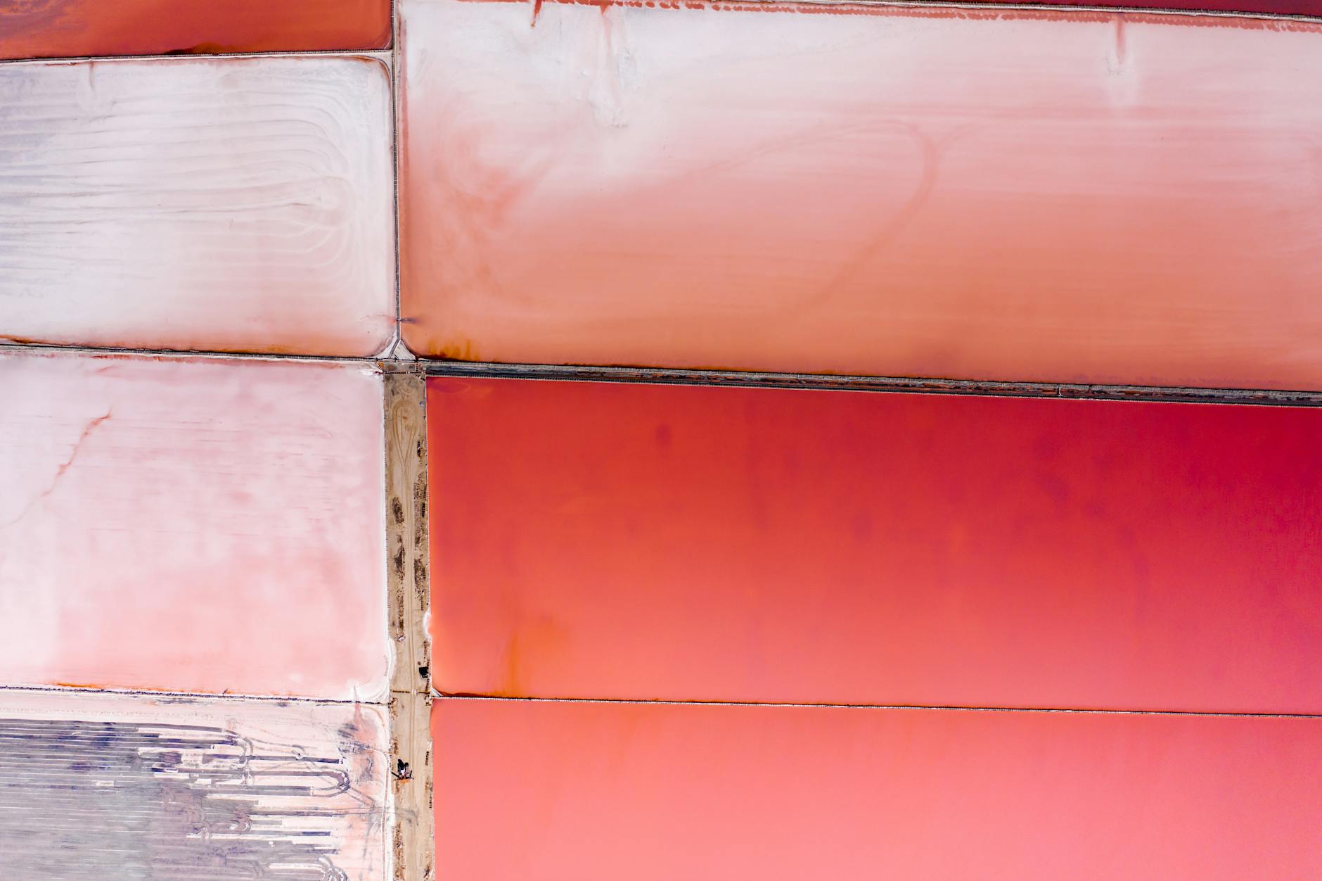 Aerial photograph showcasing colorful and geometric pink salt ponds, creating an abstract landscape.